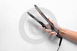 Woman holding corrugated hair iron on white background, closeup