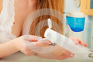 Woman holding cotton swab and makeup remover in hands