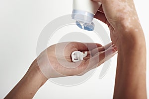 Woman holding cream tube and applying moisturizer cream on her beautiful hands