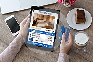 Woman holding credit card and computer tablet app hotel booking