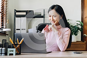 Woman holding credit card and confirm purchase via telephone call to customer service, smiling asian girl making payment