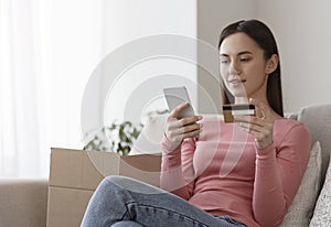 Woman holding credit card and inputting card information with cellphone