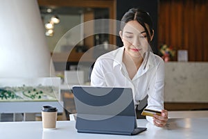 Woman holding credit card and using computer tablet for online payment or online shopping.