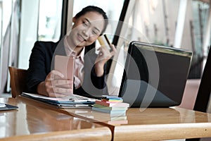 woman holding a credit card and using smart phone for online shopping at cafe. businesswoman purchase goods from internet