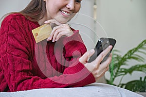 Woman holding credit card and using smartphone at home, online shopping, online banking, payment, spending money, e