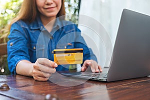 A woman holding credit cards while using laptop computer for online shopping