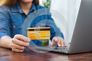 A woman holding credit cards while using laptop computer for online shopping