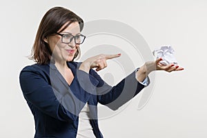 Woman holding a crumpled paper ball in her hand, with her finger down on the ball.