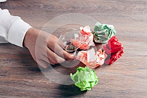 Woman holding crumpled papers and a light bulb