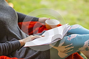 Woman holding a cup of coffee and a book