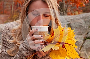 Woman holding cup of coffee in the hands outdoor. Beautiful woman drinking coffee in autumn park