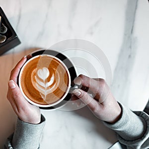Woman is holding a cup with a delicious hot latte in a vintage coffee shop. Coffee gourmet. Good morning. View from above