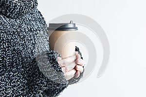 Woman holding cup of hot coffee on white wall, close up photo of hands in warm sweater with mug