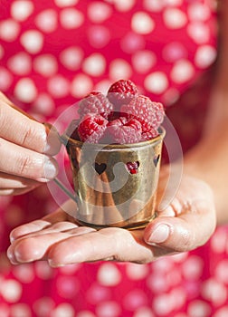 Woman holding a cup of raspberries