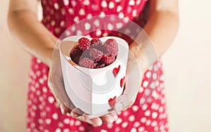 Woman holding a cup of raspberries