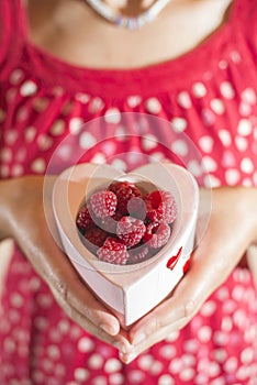 Woman holding a cup of raspberries