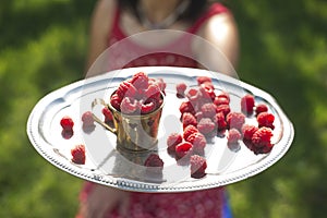 Woman holding a cup of raspberries