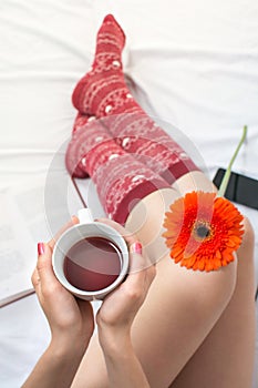 Woman holding a cup of tea in bed