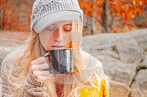 Woman holding cup of tea in the hands outdoor in autumn park