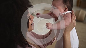 Woman holding cute baby and smiling while sitting on couch in apartment room spbd.