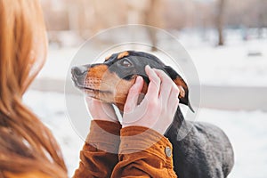 Woman holding a dachshund in her hands.