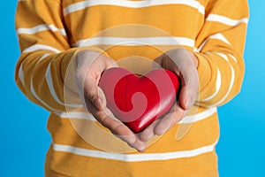 Woman holding decorative heart on color background