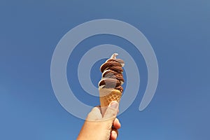 Woman holding delicious ice cream in wafer cone against blue sky, closeup