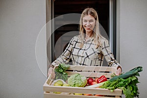Woman holding delivered crate with vegetales and fruit from local farmer, sustainable lifestyle concept. photo