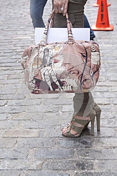 A woman holding a designer handbag and wearing booties