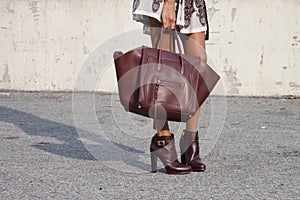 A woman holding a designer handbag and wearing booties