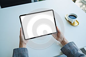 A woman holding digital tablet with blank white desktop screen in the office