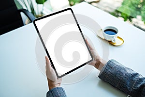 A woman holding digital tablet with blank white desktop screen in the office