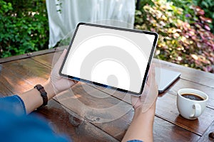 A woman holding digital tablet with blank white desktop screen in the outdoors