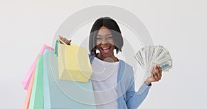 Woman holding dollar banknotes and showing her shopping bags