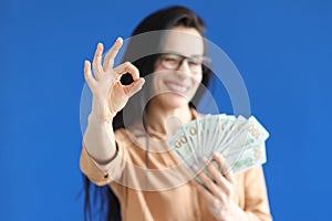 Woman holding dollar bills in her hands and showing ok gesture closeup