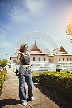 woman holding dslr camera standing outdoor with thai culture building style