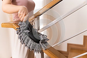 Woman holding dust wiper cleaning house stair