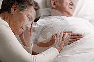 Woman holding dying husband`s hand