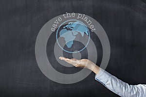 Woman holding earth front of blackboard