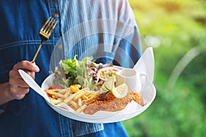 A woman holding and eating fish and chips on table in the restaurant