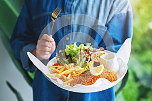 A woman holding and eating fish and chips on table in the restaurant