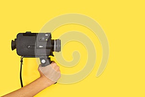 Woman holding an eight mimlimiters camera on a yellow background