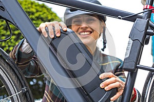 woman holding an electric bike battery mounted on frame photo