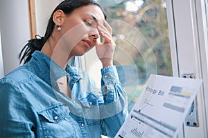 Woman holding an energy bill invoice and she is experiencing money problems