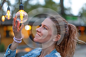 Woman holding energy efficient LED string light bulb at outdoors