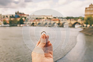 Woman holding an engagement ring front The Charles Bridge. An offer of marriage in Prague, Czech Republic.