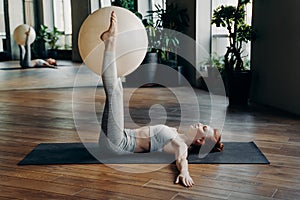 Woman holding exercise ball with straight legs on yoga mat
