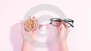 Woman holding eyeglasses in one hand and vitamins for eye health in other. How to maintain good eyesight and keep eyes healthy