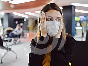 woman holding face nifiga mask waiting airport flight delay