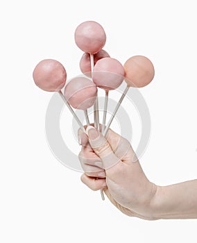 Woman holding a few pink cake pops in hand